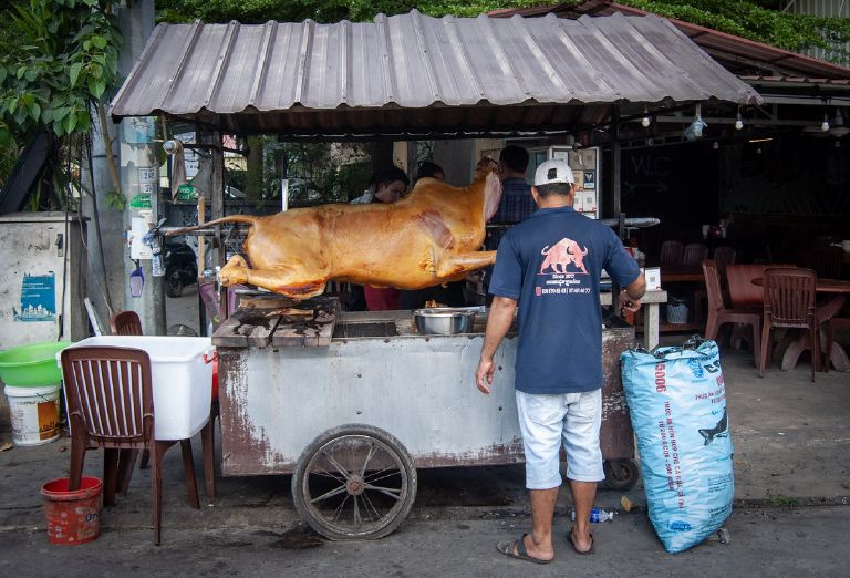 A whole cow roasting on a spit at a street food stall in Kampot