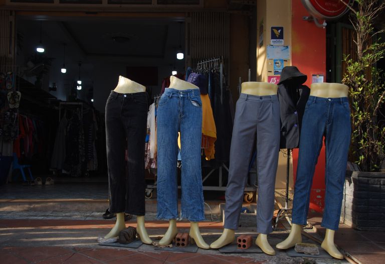 Des mannequins sans tête portant des jeans d'occasion sur le trottoir devant une friperie de Kampot