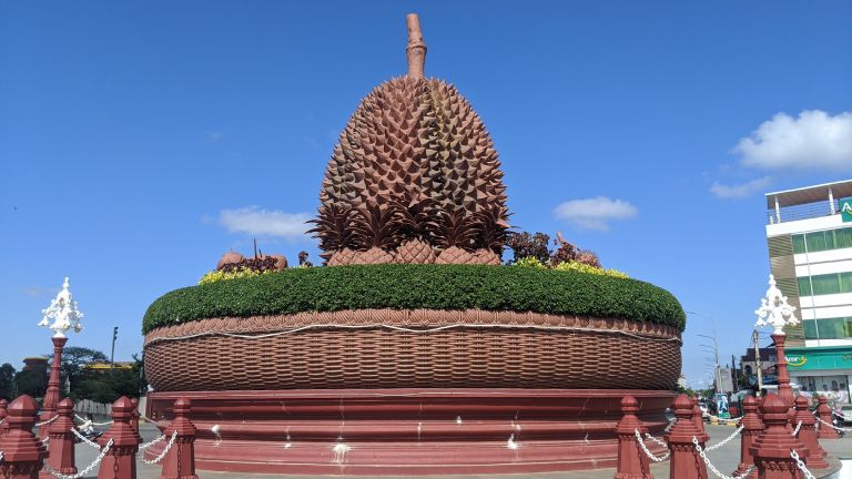 The giant durian statue at Kampot's durian roundabout, set in a woven basket against a blue sky
