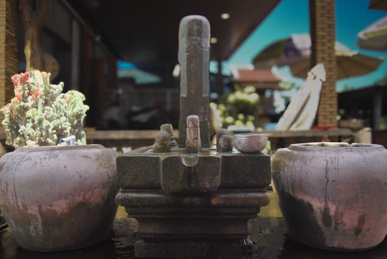 Une offrande de linga en pierre à un sanctuaire de Lok Yeay Mao sur l'autoroute entre Kampot et Phnom Penh, encadrée par deux jarres en céramique