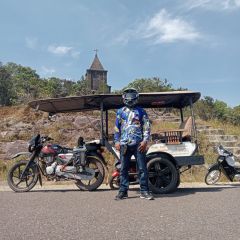 A tuk-tuk driver parked below Bokor's ruined French church