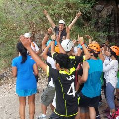 A group celebrating at the mouth of a limestone cave with Climbodia